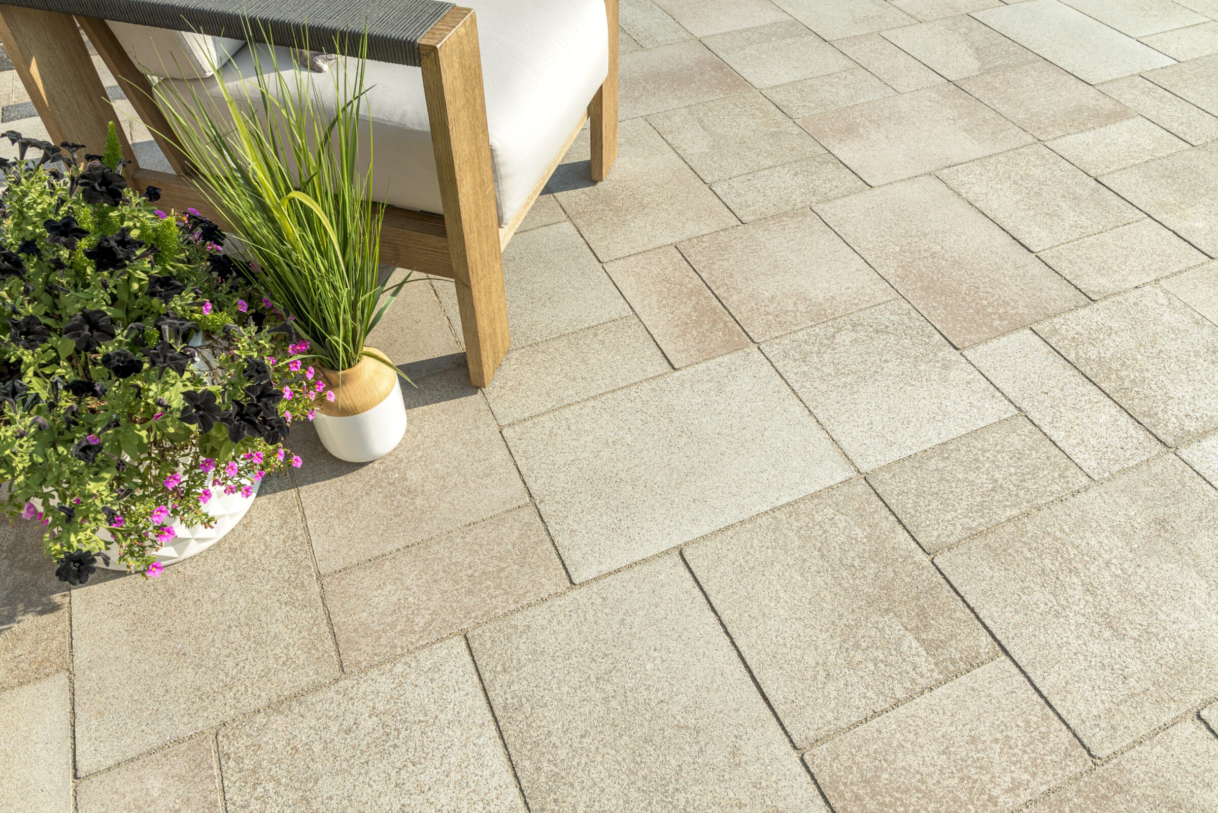 Patio with chair, potted plants, and stone tiles.