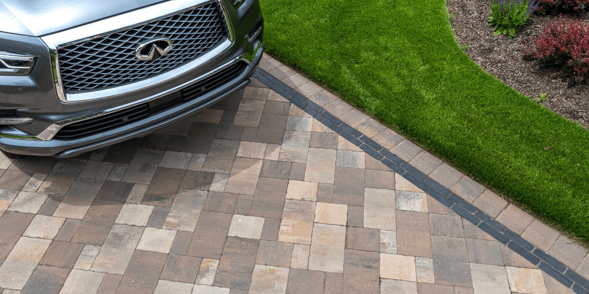 Car parked on brick driveway near green lawn