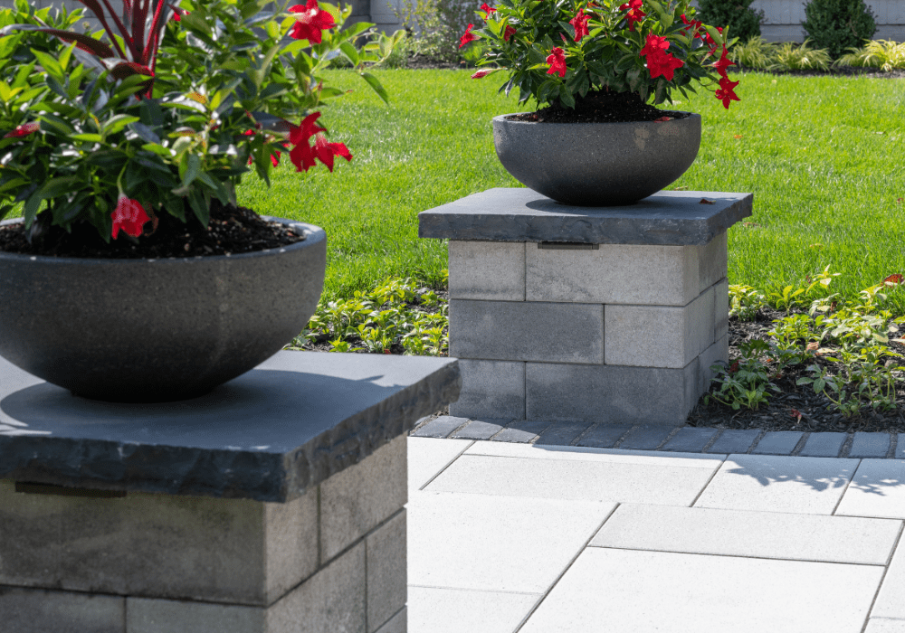 Potted flowers on stone pedestals in garden
