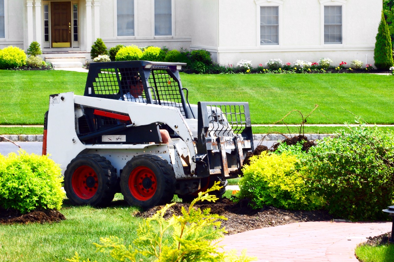 Skid steer loader working on home landscaping project.