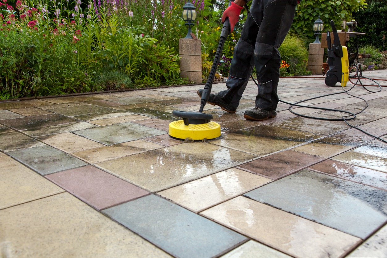 Worker pressure washing outdoor tiles