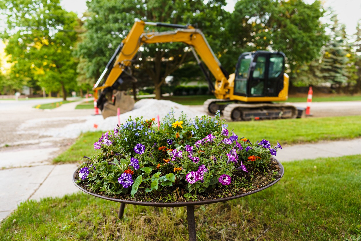 Flowers bloom near construction equipment on a street.