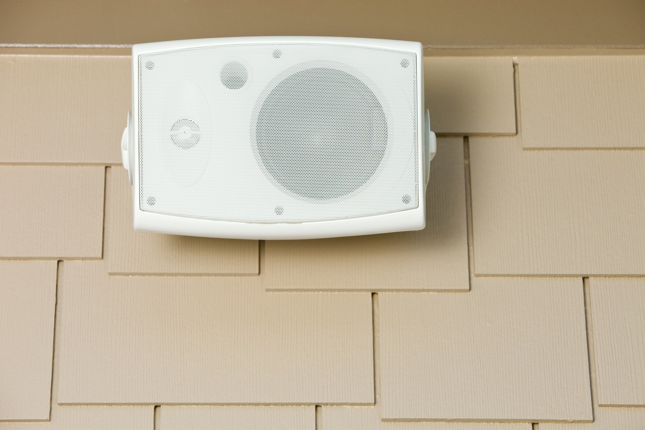 Outdoor speaker mounted on beige wall exterior