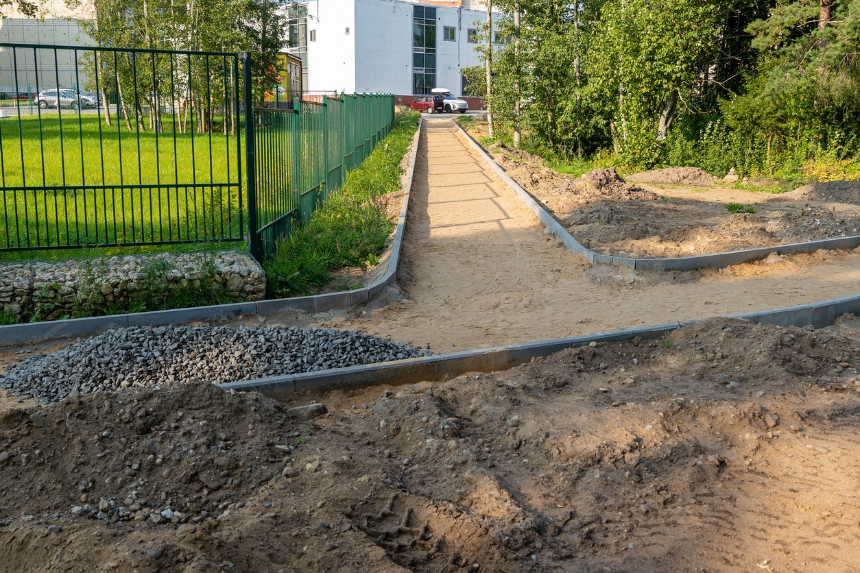 Pathway under construction with gravel and dirt piles.