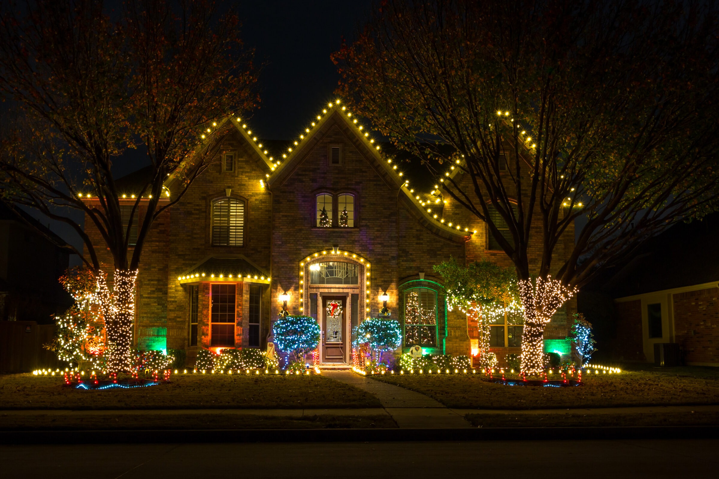 House adorned with colorful holiday lights at night.