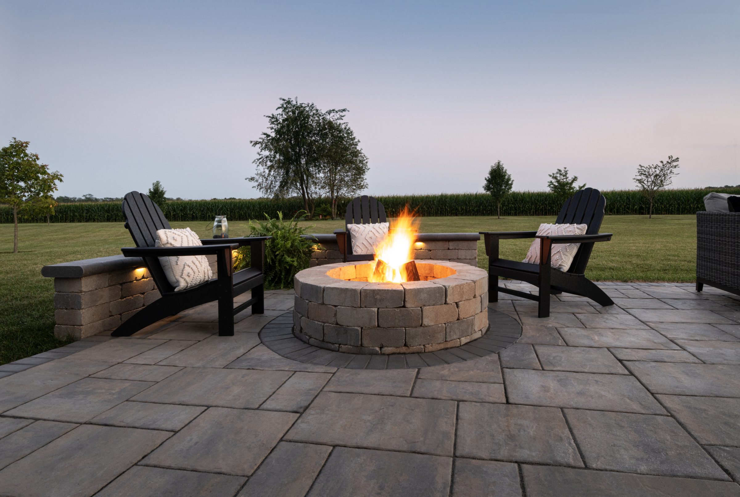 Patio with fire pit and chairs at sunset.