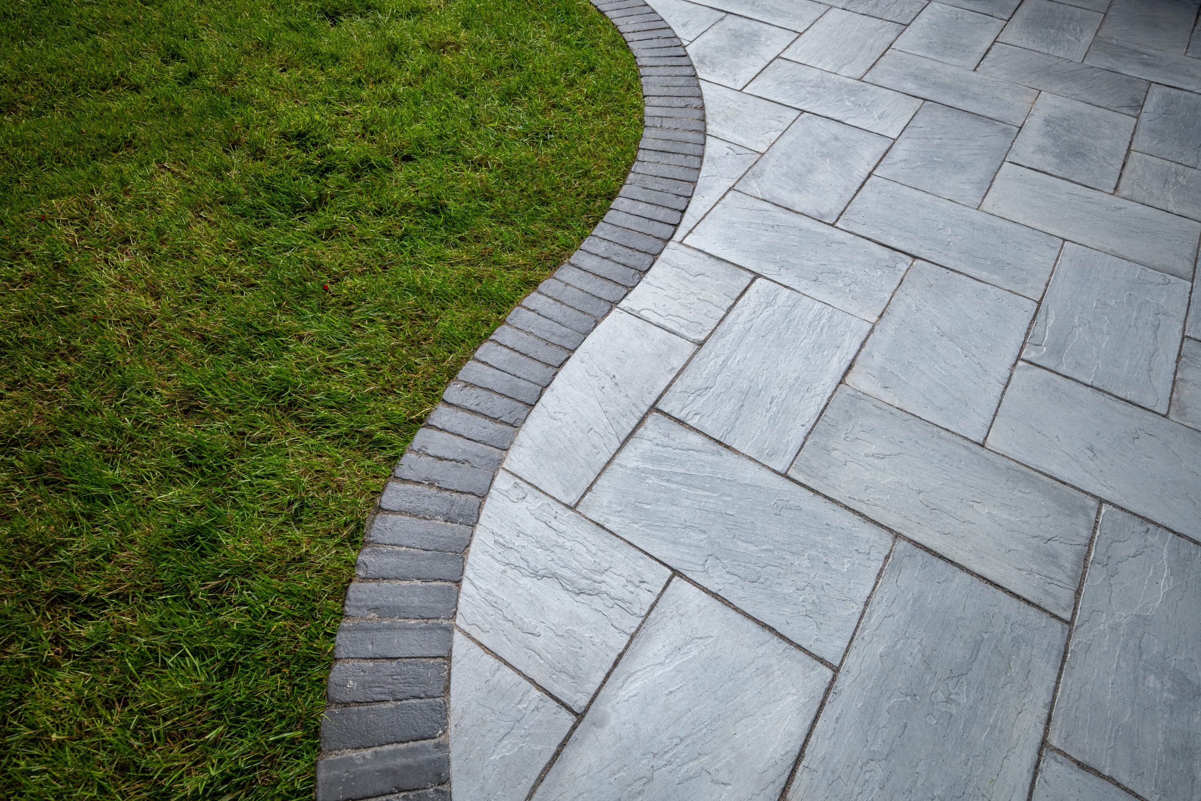Curved stone pavement beside green grass lawn