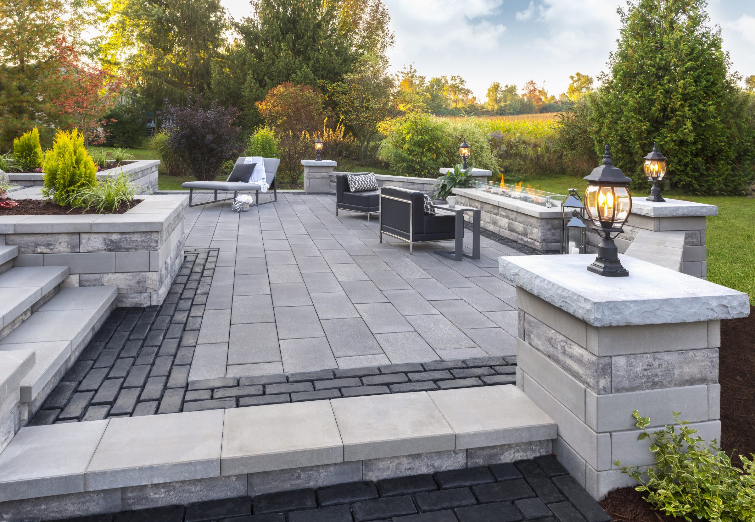 Modern backyard patio with seating and lamps.