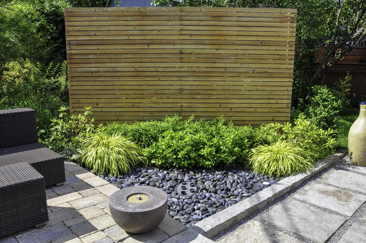 Modern garden with wooden fence and patio seating.
