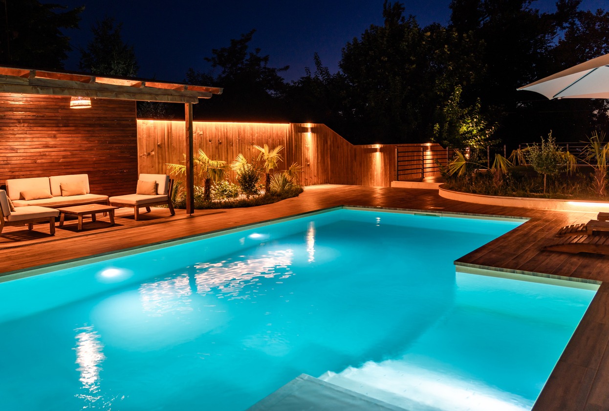 Illuminated pool with wooden deck at night